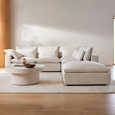 a large white couch sitting on top of a wooden floor next to a coffee table