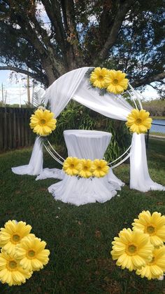 yellow flowers are placed on the grass under a white canopy