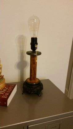 a lamp sitting on top of a wooden table next to a book and candle holder