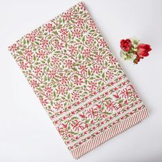 a red and green napkin next to a flower