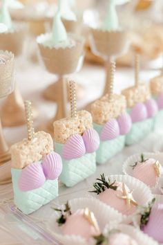 there are many desserts on the table with little boats in them, and one is pink