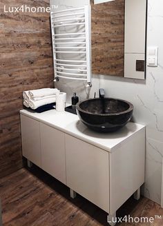 a black bowl sink sitting on top of a white cabinet next to a towel rack