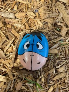 a blue and white painted rock sitting on top of dry grass