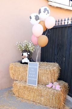 a hay bale with balloons and baby's breath sign on it in front of a gate