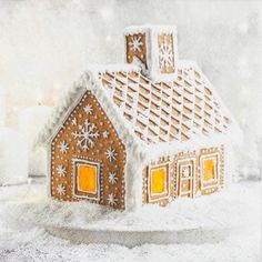 a gingerbread house with candles in the background and snowflakes on the roof