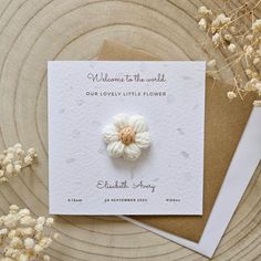 a card with a white flower on it next to some dried flowers and a brown envelope