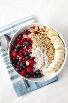 a bowl filled with yogurt and fruit on top of a blue towel next to a spoon