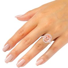 a woman's hand with pink manicured nails and an oval shaped diamond ring