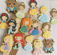 the cookies are decorated with princesses and bears on top of a wooden board,