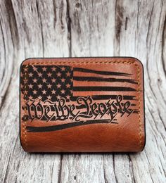 Custom made high quality hand crafted leather wallet. Perfect minimalist bifold wallet. Includes two card pockets and two stash pockets. Measures at 4"×3".  Beautiful understated "We the People" with the American flag laser engraving, wonderful patriotic gift. Enjoy a stylish and functional way to carry the essentials. Makes a wonderful gift that can be treasured for generations.  Made from the highest quality Horween leather from one of the oldest American tanneries, handcrafted to a luxurious Leather Trifold Wallet With Engraved Logo, Leather Trifold Wallet With Engraved Logo For Everyday Use, Custom Hand Tooled Leather Trifold Wallet, Custom Hand-tooled Trifold Wallet, Custom Hand-tooled Rectangular Trifold Wallet, Custom Leather Wallet, Horween Leather, We The People, Clip Wallet