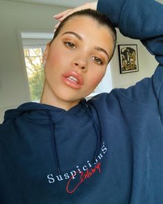 a woman wearing a blue sweatshirt with the word supplicans on it and her hair up