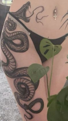 a woman with tattoos on her stomach holding a plant