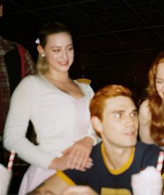 a group of people sitting around each other at a table with drinks in front of them