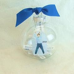 a small glass ornament with a blue ribbon on it's end and a man in the middle