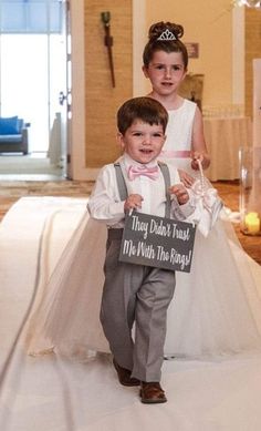 two young children dressed in wedding attire holding signs