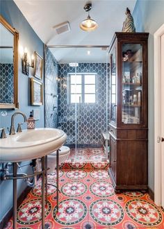 a bathroom with a sink, mirror and cabinet in the corner next to it is tiled flooring