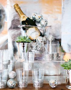 a table topped with lots of glasses and a bottle of champagne on top of it