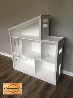 a white book shelf sitting on top of a hard wood floor next to a wall