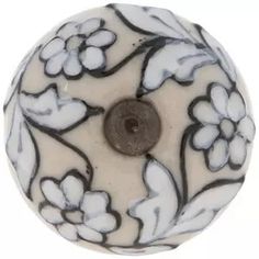 a white and black flowered bead with a brown button on the center is shown