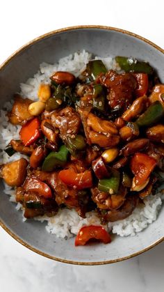 a white bowl filled with rice and meat on top of a table next to a fork