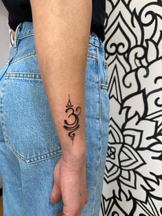 a person with a small tattoo on their left arm and the word om written in black ink