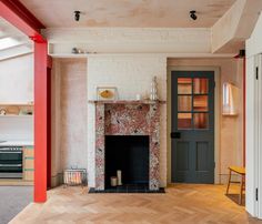 an empty living room with a fireplace and red painted columns on the wall next to it