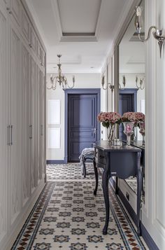 the hallway is decorated in blue and white with floral arrangements on the end table next to it