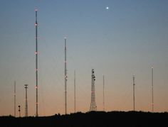 several cell towers are silhouetted against the evening sky