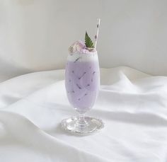 a purple drink in a glass with a green leaf garnish on the rim