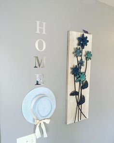 there is a blue flower on the wall next to a hat rack and a sign that says home