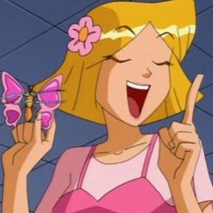 a woman with blonde hair and pink dress holding a butterfly in her hand while making the peace sign