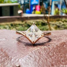 a princess cut diamond ring sitting on top of a rock