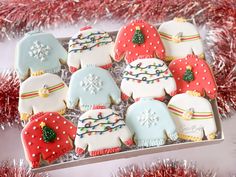 decorated christmas cookies on a tray with red tinsel