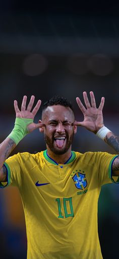 a man with his hands up in the air and making a funny face while wearing a yellow shirt