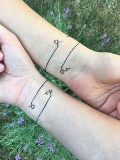 two people holding hands with tattoos on them