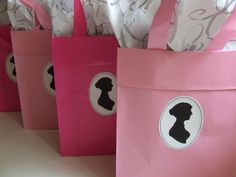 pink paper bags with silhouettes on them are sitting next to each other in front of a white wall