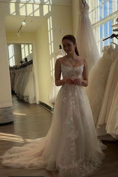 a woman is standing in front of wedding dresses