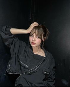 a young woman is posing for the camera in a dark room with her hand on her head