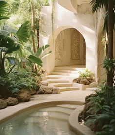 an indoor swimming pool surrounded by greenery and rocks with steps leading up to it