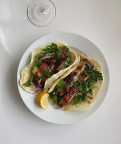 two tacos on a plate with a glass of wine