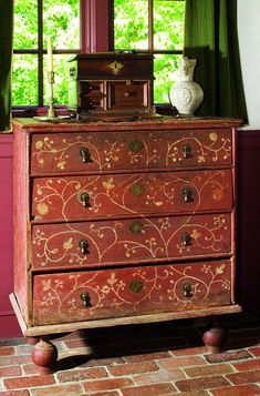 an old chest of drawers in front of a window