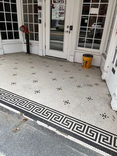 an entrance to a building with white doors and black and white tile on the floor