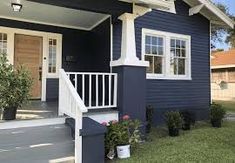 a blue house with white trim on the front porch