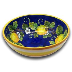 a blue and yellow bowl with fruit painted on the side, sitting in front of a white background