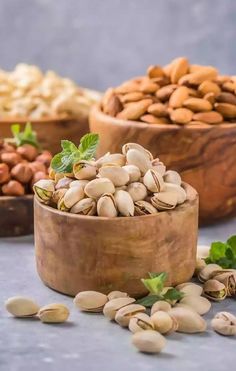 nuts in wooden bowls with green leaves on the side and other nuts scattered around them