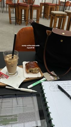 a laptop computer sitting on top of a table next to a cup of coffee and notebook