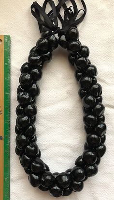 a black beaded bracelet next to a ruler