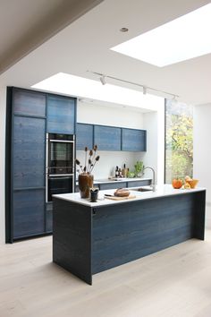 an open kitchen with blue cabinets and white counter tops, along with a skylight