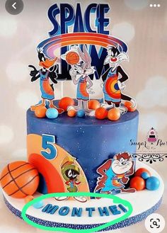 a birthday cake decorated with cartoon characters and basketballs is shown on a tablecloth