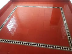 a red tiled floor with black and white checkered border